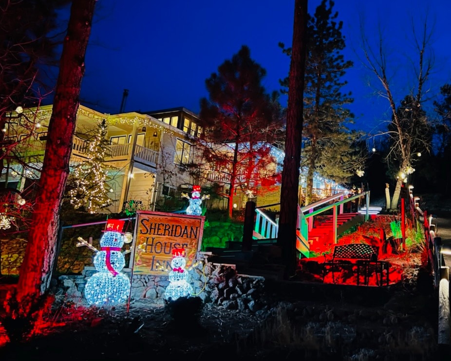 front of inn with christmas lights, pine trees and large lighted snowmen by the sign that says Sheridan House Inn