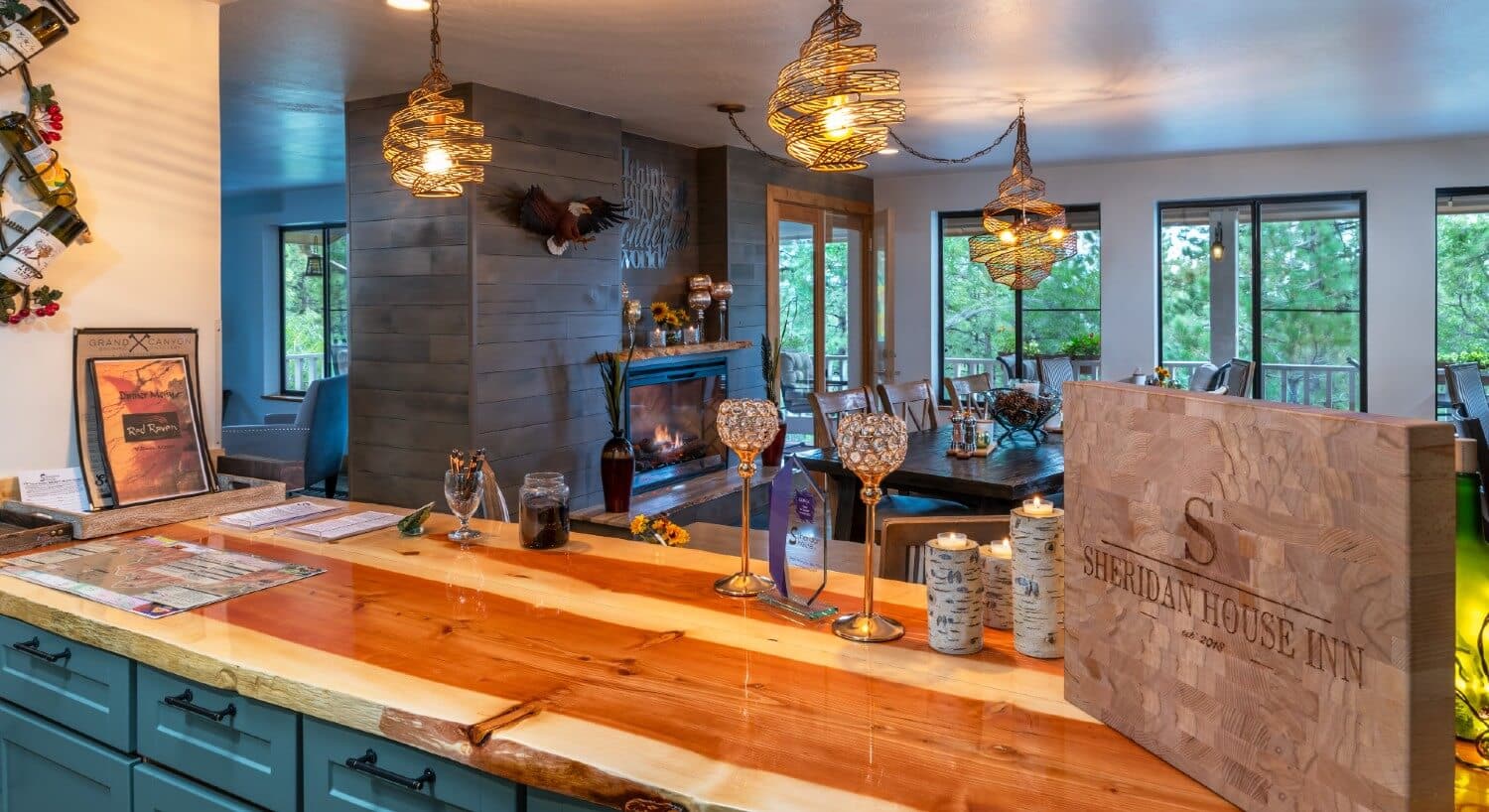 wood countertop with small chandeleirs with dining room and picture windows in background